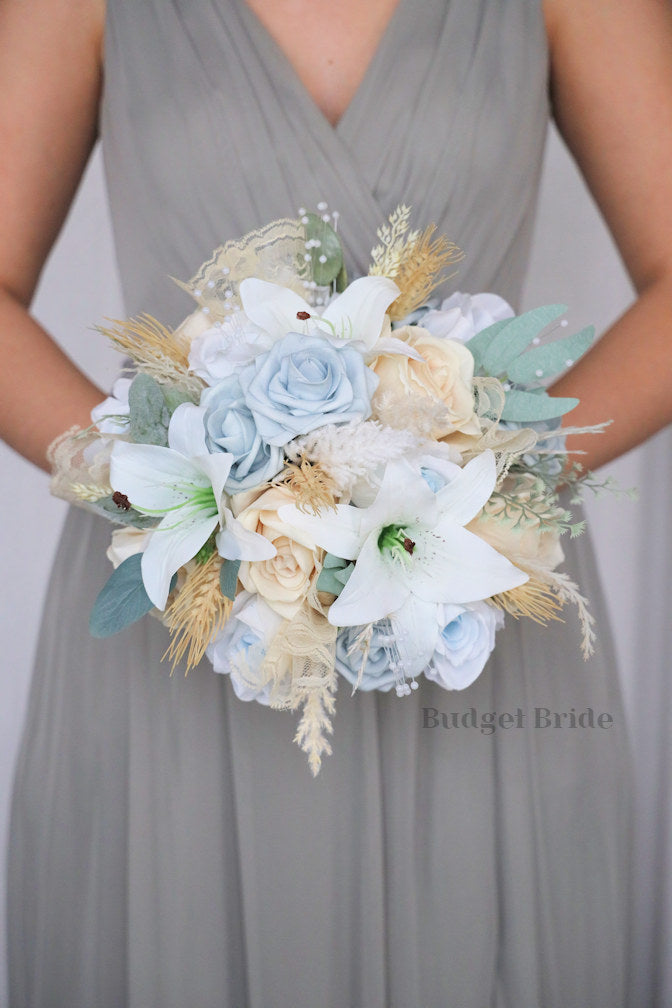 White tiger lilies, dusty blue and peach roses, pearls, pampas grass and wheat in artificial flower brides bouquet