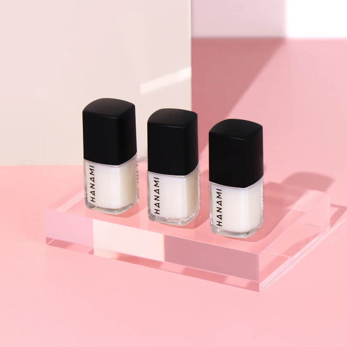 Three Hanami nail polish bottles on a pink platform with a light pink background.