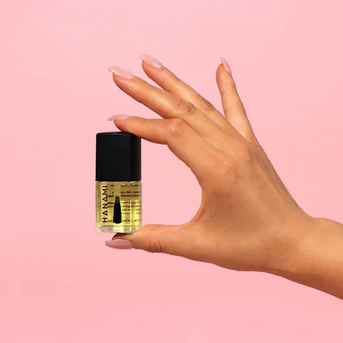 Hand holding a small bottle of Hanami nail polish against a pink background.