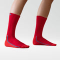 A pair of legs wearing bright red, calf-length socks with blue trim on a plain white background. The feet are slightly apart, and only the lower legs are visible.