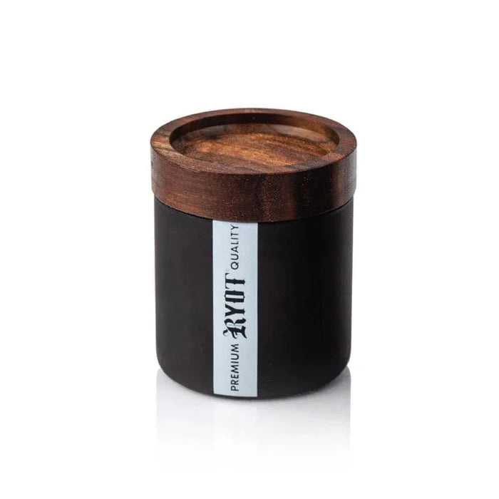 A side view of the RYOT Glass Jar with Tray Lid, featuring a dark wooden lid and clear glass base on a reflective surface.