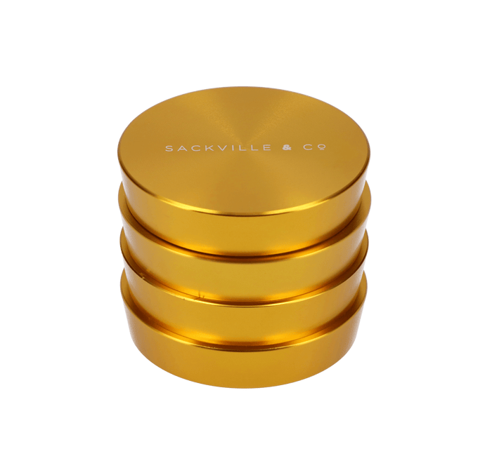 A close-up, angled view of the gold Sackville and Co 4pc Grinder, showcasing its four stacked pieces.