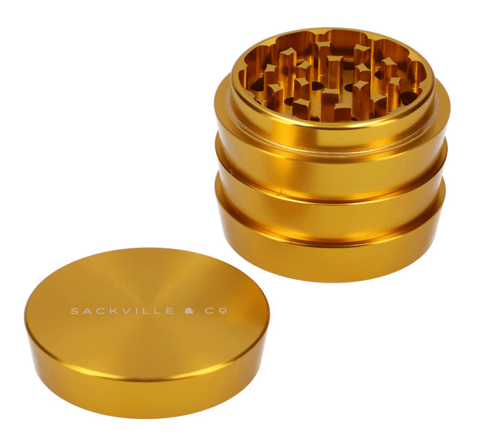 A close-up of the gold Sackville and Co 4pc Grinder, showcasing its four-tiered cylindrical design.